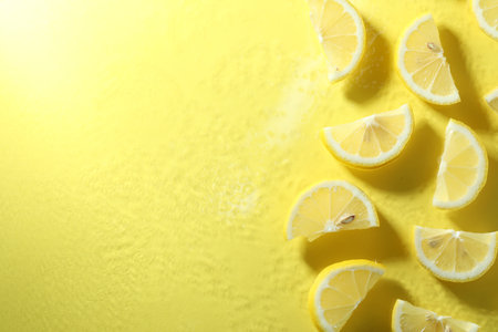 Fresh lemon slices with water drops on yellow background, top view. Space for textの写真素材