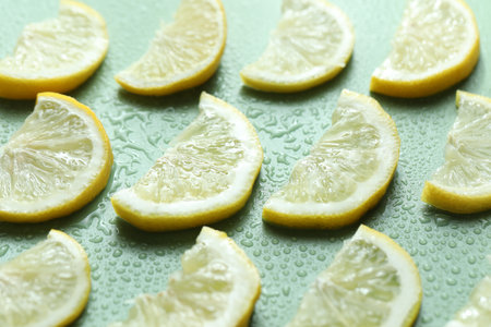 Slices of lemon and water drops on light green background, closeupの写真素材