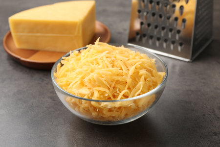 Grated and piece of cheese with grater on gray table, closeupの写真素材