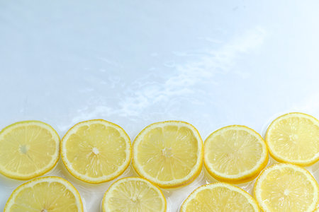 Slices of lemon in water on light background, above view. Space for textの写真素材