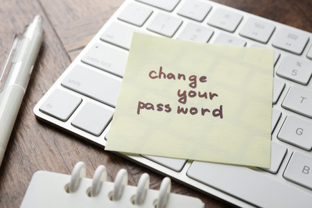 Note with phrase Change your password, keyboard and stationery on wooden desk, closeupの写真素材