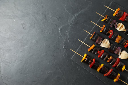 Skewers with tasty grilled vegetables on black table, top view. Space for textの写真素材