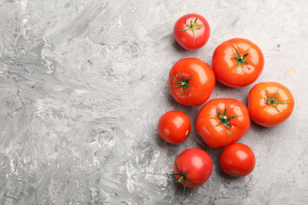 Fresh ripe tomatoes on gray textured table, flat lay. Space for textの写真素材