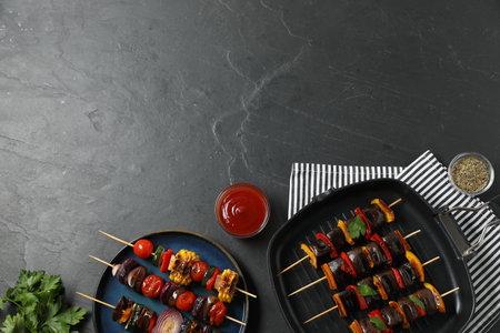 Skewers with tasty grilled vegetables served on black table, flat lay. Space for textの写真素材