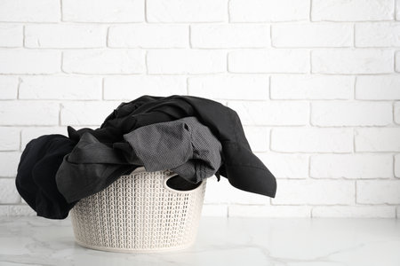 Laundry basket full of clothes on white marble surface. Space for textの写真素材