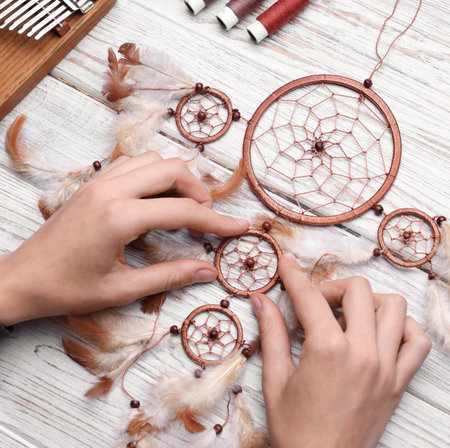 Woman making beautiful dream catcher at light wooden table, above viewの写真素材