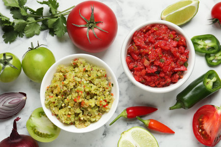 Tasty salsa in bowl and ingredients on white marble table, flat layの写真素材