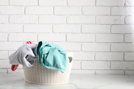 Laundry basket full of clothes on white marble surface. Space for textの写真素材