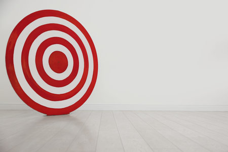 Round shooting target on floor near white wall, space for textの写真素材
