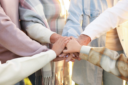 Parents and their children holding hands outdoors, closeup. Family bonding