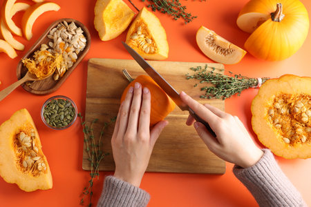 Woman cutting pumpkin on orange background, above viewの写真素材