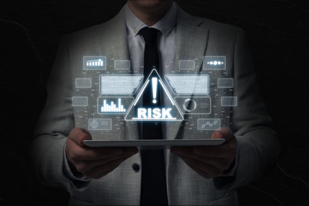 Man holding tablet computer in darkness, closeup. Warning sign with word Risk and data above deviceの写真素材