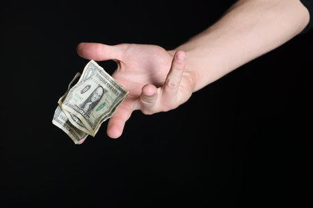 Man throwing money on black background, closeup