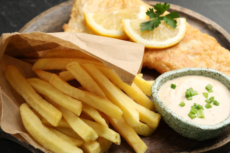 British Traditional Fish and chips with sauce, lemon and parsley on table, closeupの写真素材