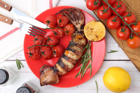 Tasty stuffed squid, rosemary, lemon and tomatoes on light wooden table, flat layの写真素材