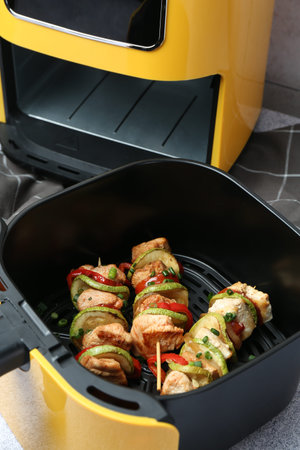 Tasty skewers with chicken and vegetables in air fryer on light gray table, closeupの写真素材