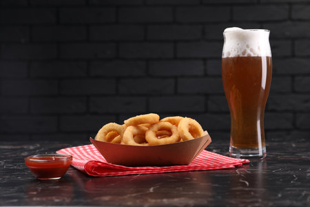 Fried squid rings with sauce and beer served on black marble table. Space for textの写真素材