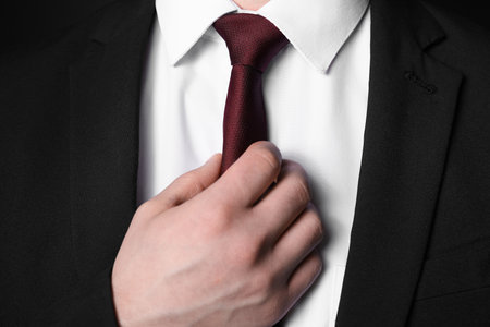 Man in suit adjusting his necktie, closeupの写真素材