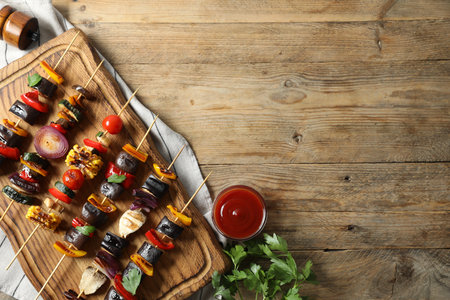 Skewers with tasty grilled vegetables and sauce on wooden table, top view. Space for textの写真素材