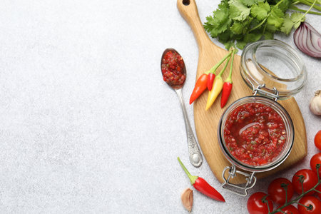 Tasty salsa sauce in jar and ingredients on light table, flat lay. Space for textの写真素材