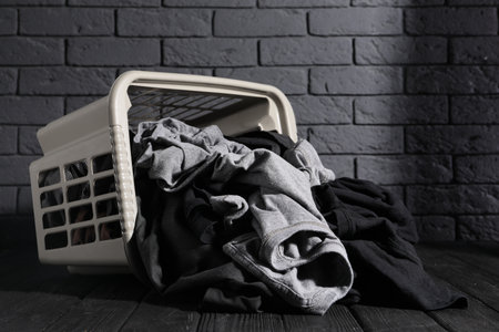 Overturned laundry basket with clothes on black wooden surfaceの写真素材