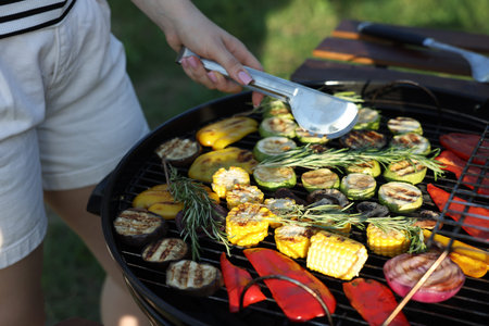 Vegetarian barbeque. Woman cooking vegetables on grill outdoors, closeupの写真素材