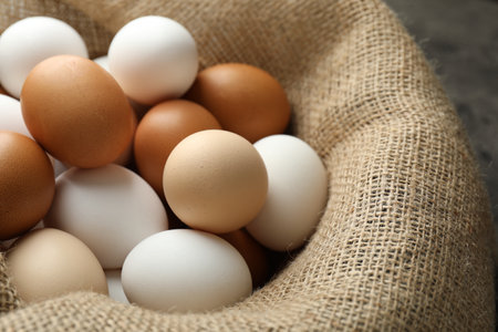 Many raw chicken eggs in sack on gray table, closeupの写真素材