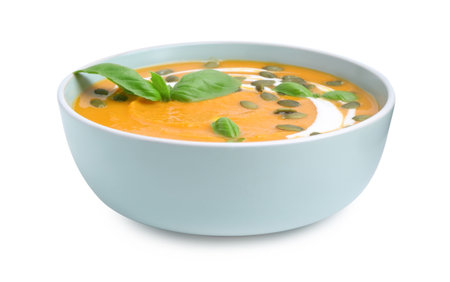 Delicious pumpkin soup with seeds and basil in bowl isolated on whiteの写真素材