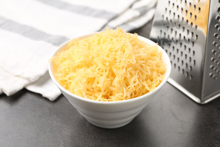 Grated cheese and grater on gray table, closeupの写真素材