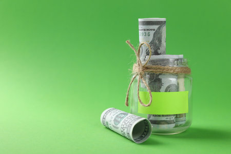 Jar with blank note and money on green background. Space for textの写真素材