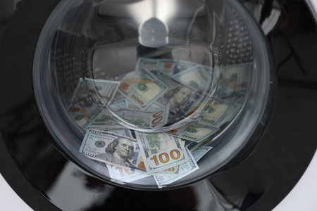 Money laundering. Many dollar banknotes in washing machine, closeupの写真素材