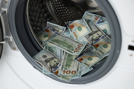 Money laundering. Many dollar banknotes in washing machine, closeupの写真素材