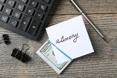 Note with word Alimony, money, pen, clips and calculator on wooden table, flat layの写真素材