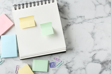 Blank notes and notebook on white marble table, flat lay. Space for textの写真素材