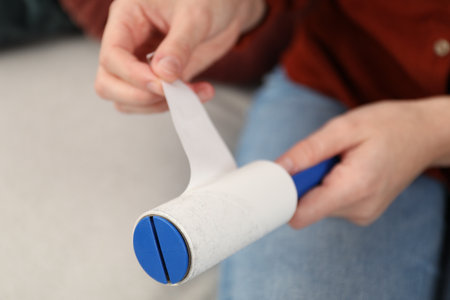 Woman removing sticky tape from lint roller at home, closeupの写真素材