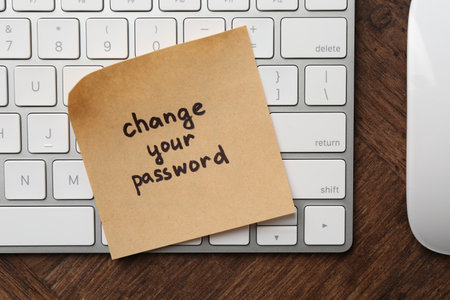 Note with phrase Change your password and keyboard on wooden desk, top viewの写真素材