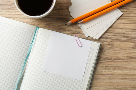 Blank notes, notebook, cup of coffee and pencils on wooden table, flat lay. Space for textの写真素材