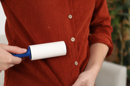 Woman using lint roller at home, closeupの写真素材