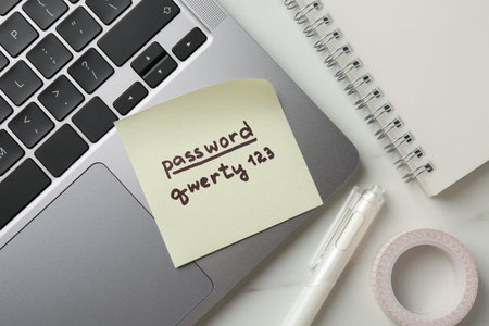 Paper note with password, laptop and stationery on white table, flat layの写真素材