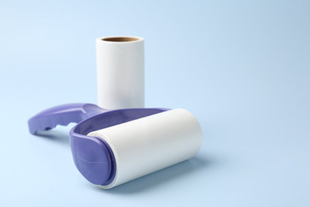 Lint roller and adhesive roll on light blue background, closeup. Space for textの写真素材