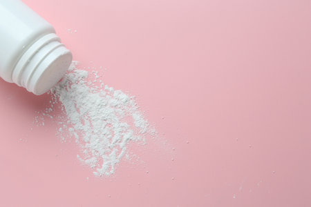 Bottle of talcum powder on pink background, top view. Space for textの写真素材