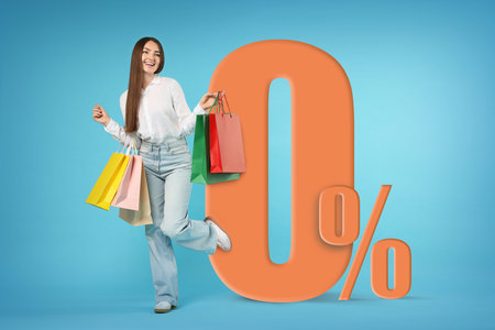 Happy woman with shopping bags on light blue background. 0 percent sign near her