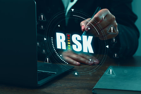Businesswoman using virtual screen with the word Risk and warning signs above laptop, closeupの写真素材