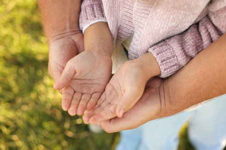 Father with his daughter holding hands outdoors, closeup. Family bondingの写真素材