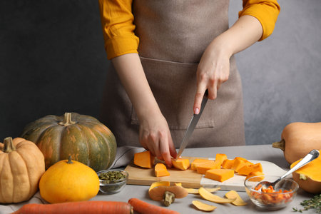 Woman cutting pumpkin at gray table, closeupの写真素材