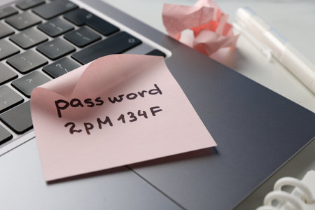 Paper note with password, laptop and stationery on white table, closeupの写真素材