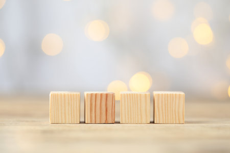 Blank cubes on wooden table against blurred background, space for text. Bokeh effectの写真素材