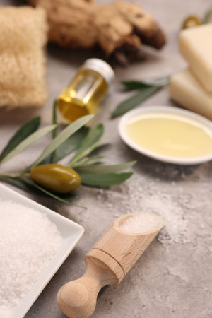 Handmade soap bars, olives, green leaves, oil and sea salt on gray textured table, closeupの写真素材