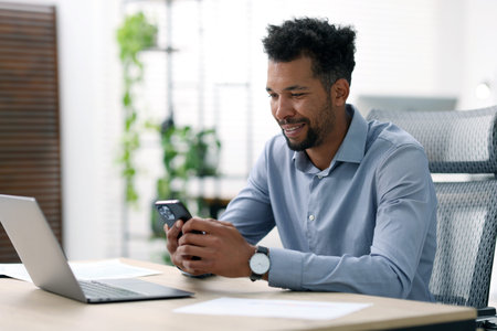 Man using smartphone at table in officeの写真素材