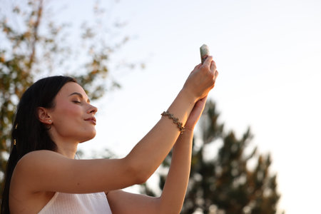 Woman meditating with crystal to heal or restore her aura outdoors, low angle view. Space for textの写真素材